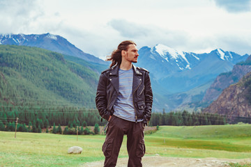 the guy stands against the background of snowy mountains