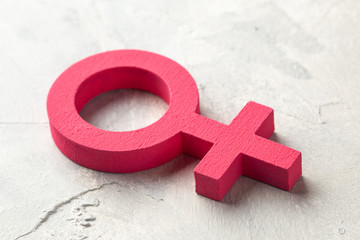 Gender symbols of a woman of pink color on a gray background