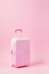 Miniature pink suitcase. Travel preparation, tourism, hand luggage, low cost flights, vacations baggage packing concept