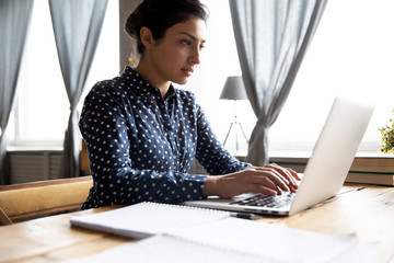 Serious indian woman student professional using laptop sit at desk