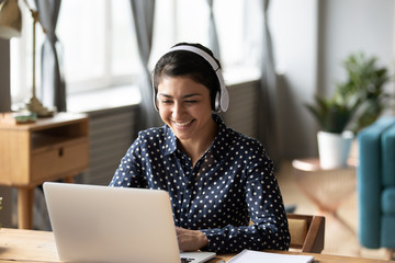 Happy indian young girl wear headphones watching listening online course
