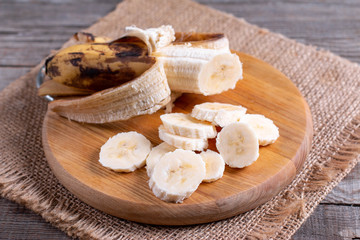 Slices banana on cutting board and wood background