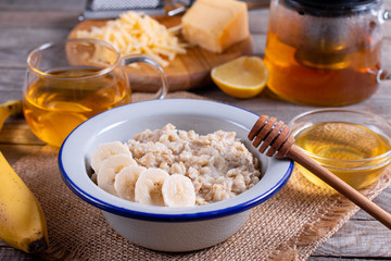 Oatmeal porridge with cheese and banana on a white plate on a wooden background