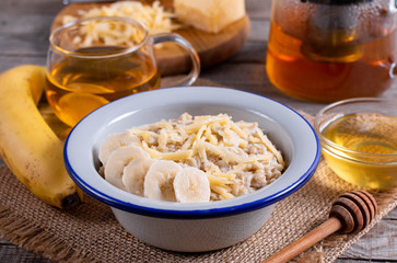 Oatmeal porridge with cheese and banana on a white plate on a wooden background