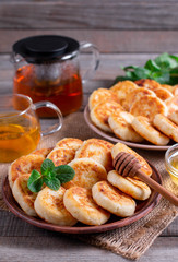 Cottage cheese pancakes, syrniki with honey on a plate on wooden background