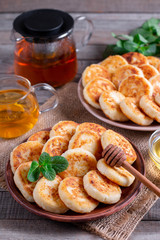 Cottage cheese pancakes, syrniki with honey on a plate on wooden background