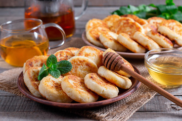 Cottage cheese pancakes, syrniki with honey on a plate on wooden background
