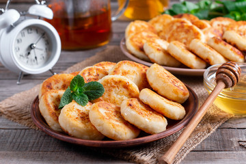 Cottage cheese pancakes, syrniki with honey on a plate on wooden background