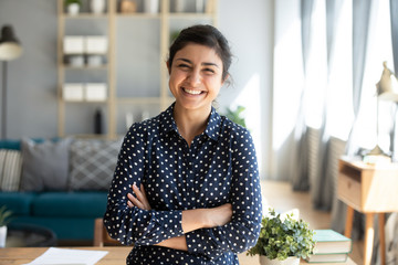 Smiling indian woman looking at camera posing at modern home