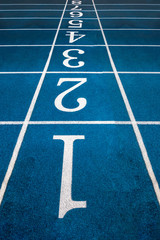 Blue running treadmill track with lane numbers in stadium outdoors.Starting grid of race track at the stadium