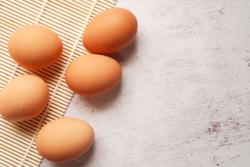 top view of group of chicken eggs on bamboo mat on concrete texture background with copy space ,minimal style