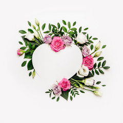 Obraz na płótnie Canvas Valentine's day romantic concept. Natural heart shape frame layout with white and pink roses and green leaves