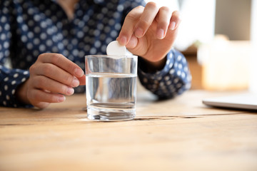 Fototapeta na wymiar Sick woman drop effervescent aspirin into water glass take medicine