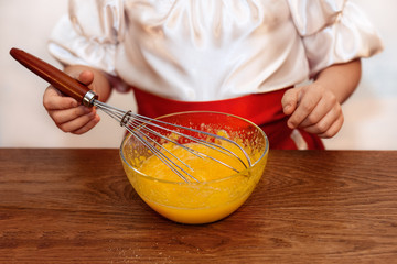 Little girl mixing eggs in the bowl