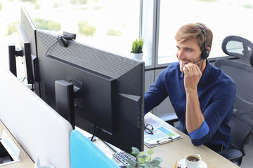 Happy young male customer support executive working in office.