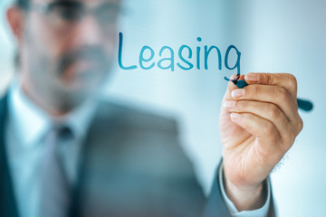 Businessman write the word Leasing and give a brief property, buildings, vehicles are common assets that are leased. - obrazy, fototapety, plakaty