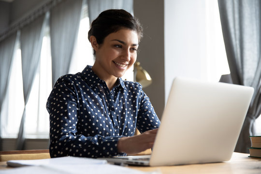 Smiling Indian Girl Student Professional Typing On Laptop At Table