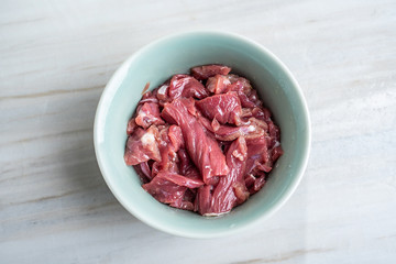A bowl of cured beef on a kitchen tile countertop plate