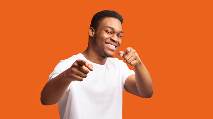 Happy black man choosing you over orange background - obrazy, fototapety, plakaty