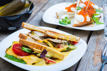 Classic breakfast, hot sandwiches with cheese, vegetables and chicken on a wooden table. Hand-made, rustic breakfast, toast with turkey and vegetables. Soft focus.