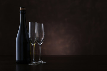 Bottle of champagne and two glasses on brown background