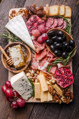 Traditional italian antipasto plate. Assorted cheeses on wooden cutting board. Brie cheese, cheddar...
