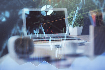 Stock market graph on background with desk and personal computer. Double exposure. Concept of financial analysis.