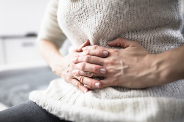 Tired exhausted woman with stomach issues at home on a couch, be