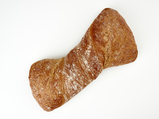 Fresh dark ciabatta lies on a light background.