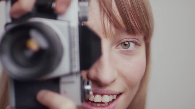 Polish lady with green eyes posing with a photography film camera, closeup