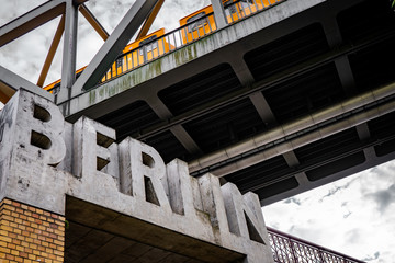 yellow train on a bridge above berlin lettering