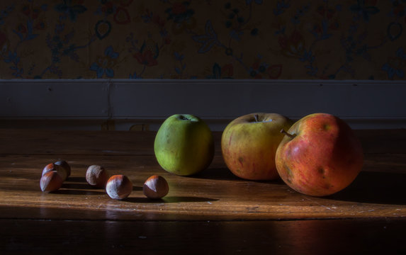 Nature morte: pommes et noisettes sur une table en bois ancienne
