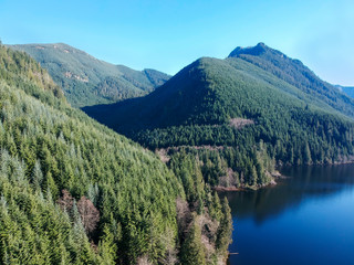 Fototapeta na wymiar Rarely seen beautiful aerial photographs of Calligan Lake in Washington State with green mountainside open vistas clouds blue sky and shoreline on a warm autumn day.