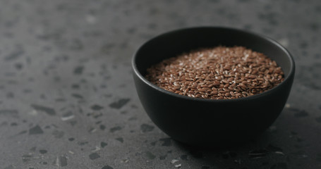 flaxseed in black bowl on terrazzo countertop with copy space