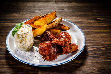 Barbecue chicken drumsticks with baked potatoes and coleslaw