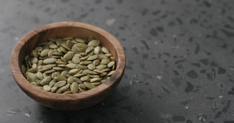 pumpkin seeds in olive bowl on terrazzo countertop with copy space