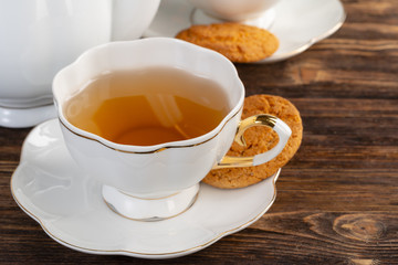 White porcelain cup of tea and oat cookies on a table