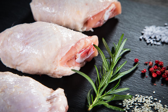 Raw chicken thigs on black stone on wooden background
