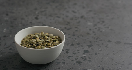 pumpkin seeds in white bowl on terrazzo countertop with copy space