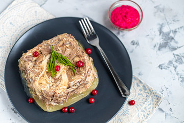 Jelly with meat, pork and chicken, aspic. Traditional Russian dish, serving on a dark plate next to...