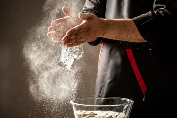 splash white flour on black background and hands