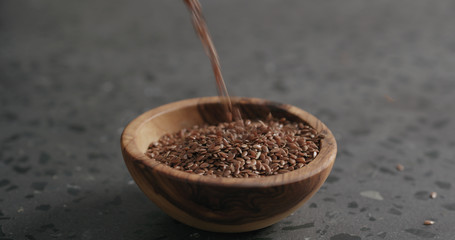 flaxseed falling into olive bowl on terrazzo countertop