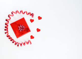 Gift in red packaging with hearts and a packing tape on a white background. Horizontal orientation, copy space, top view.