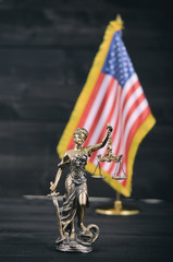 Scales of Justice, Justitia, Lady Justice in front of the American flag in the background.