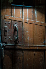 An old wooden door is padlocked and illuminated by a lantern