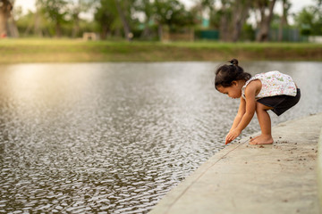 Fototapeta premium Little girl playing along the pond.