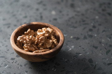 Fototapeta na wymiar Walnuts in wooden bowl on terrazzo countertop with copy space