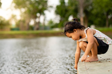 Fototapeta premium Little girl playing along the pond.