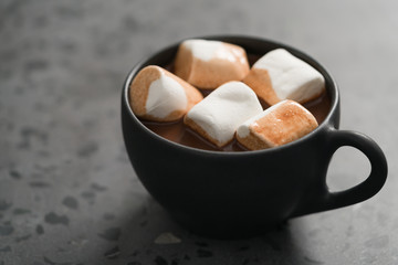 cup of hot cocoa with marshmallow on terrazzo background