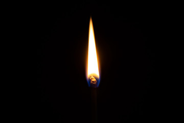 Safety match burns in front of isolated dark background